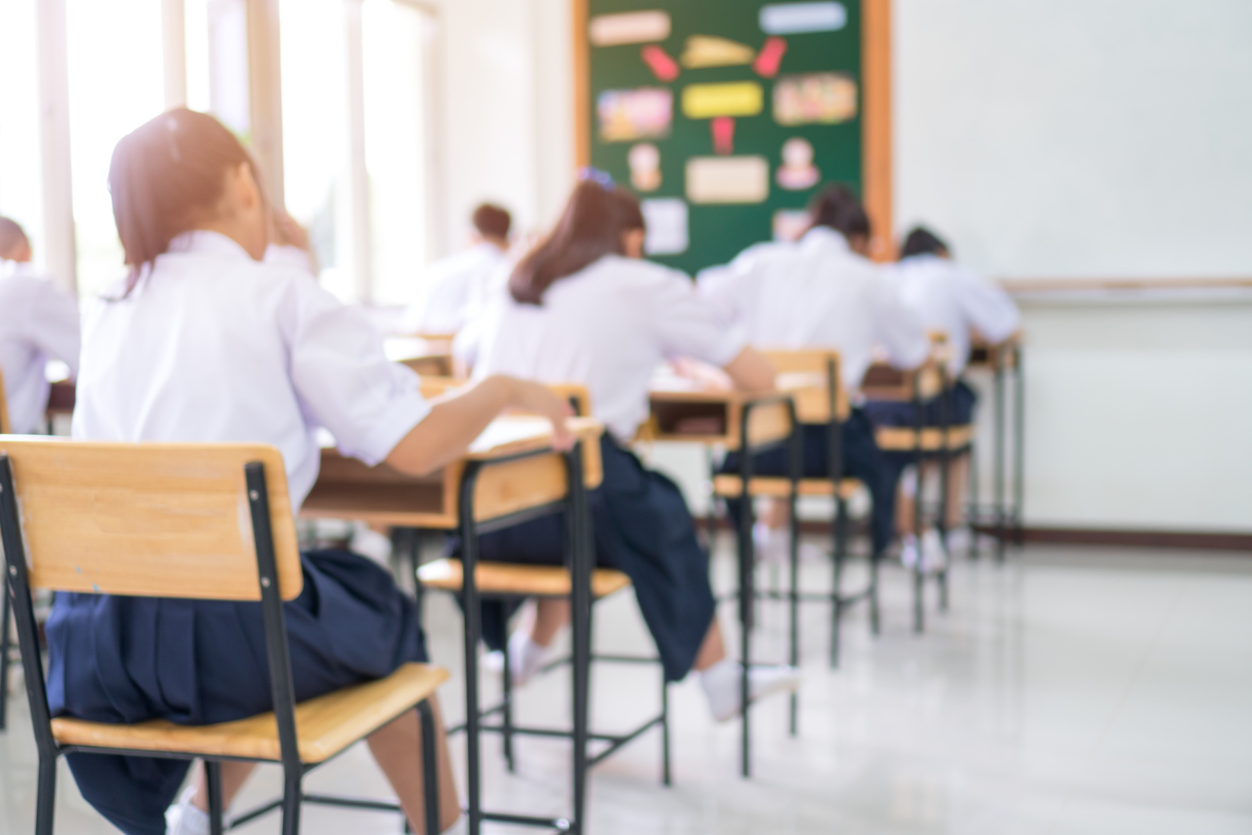 Exam for Education uniform students testing exams with pencil for multiple-choice quizzes or test answer sheets exercises in school rows chairs at classroom in Thailand, Behind Asian back to school